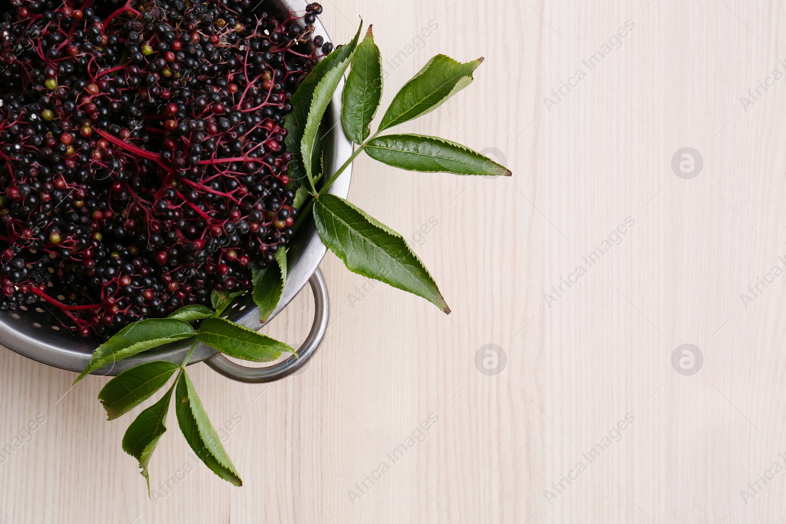 Photo of Tasty elderberries (Sambucus) on wooden table, top view. Space for text