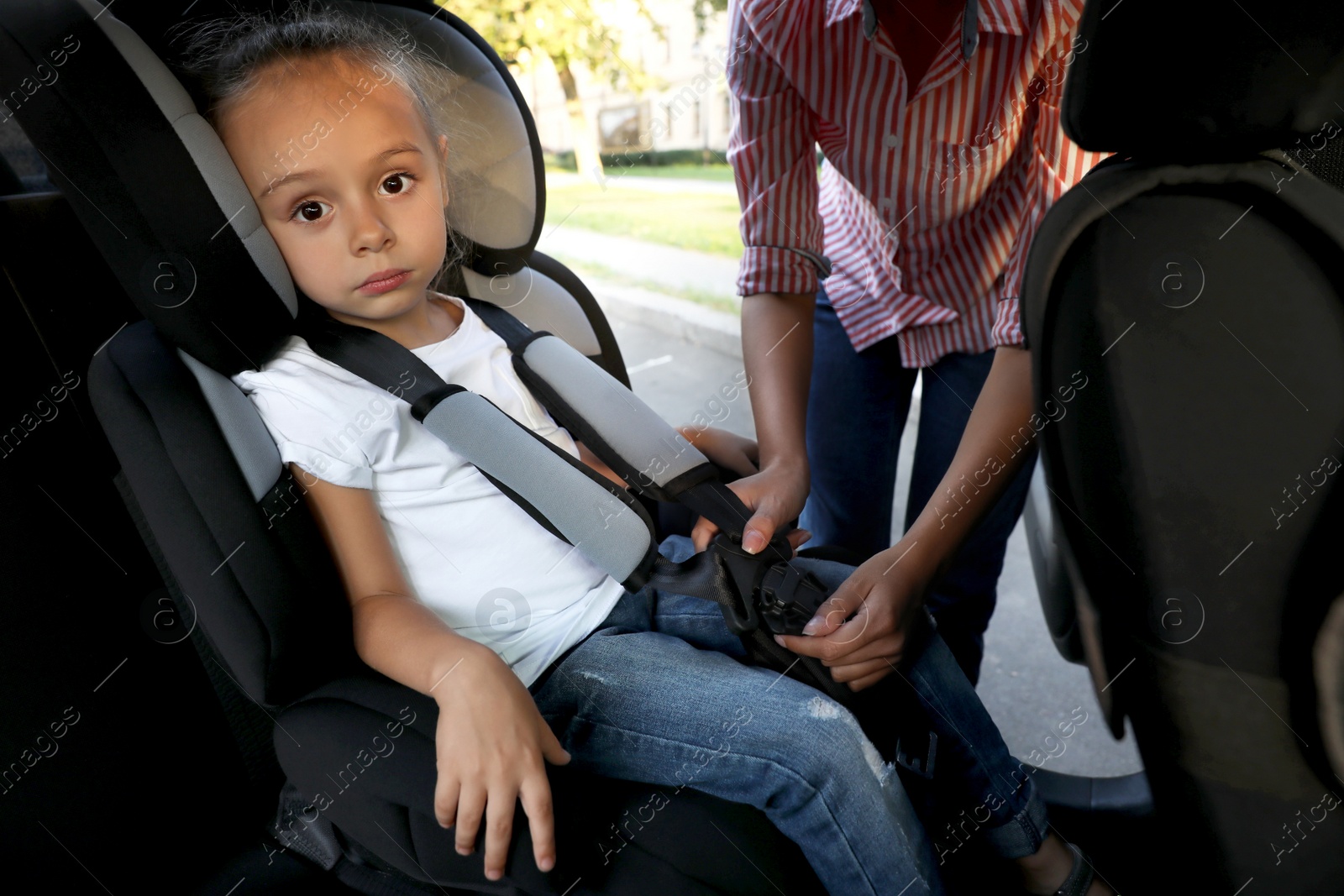 Photo of Mother fastening her daughter with car safety seat belt. Family vacation