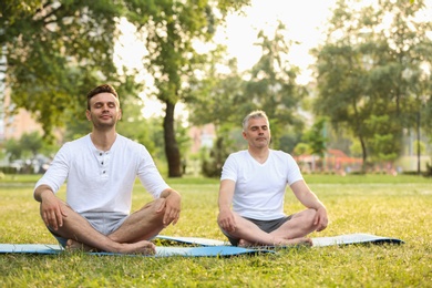 Men practicing yoga in park at morning