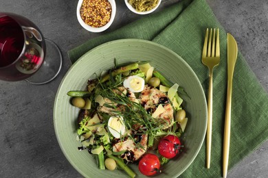 Photo of Delicious dish with tarragon, salad dressings and glass of wine served on grey table, flat lay