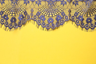 Blue lace on yellow background, top view. Space for text