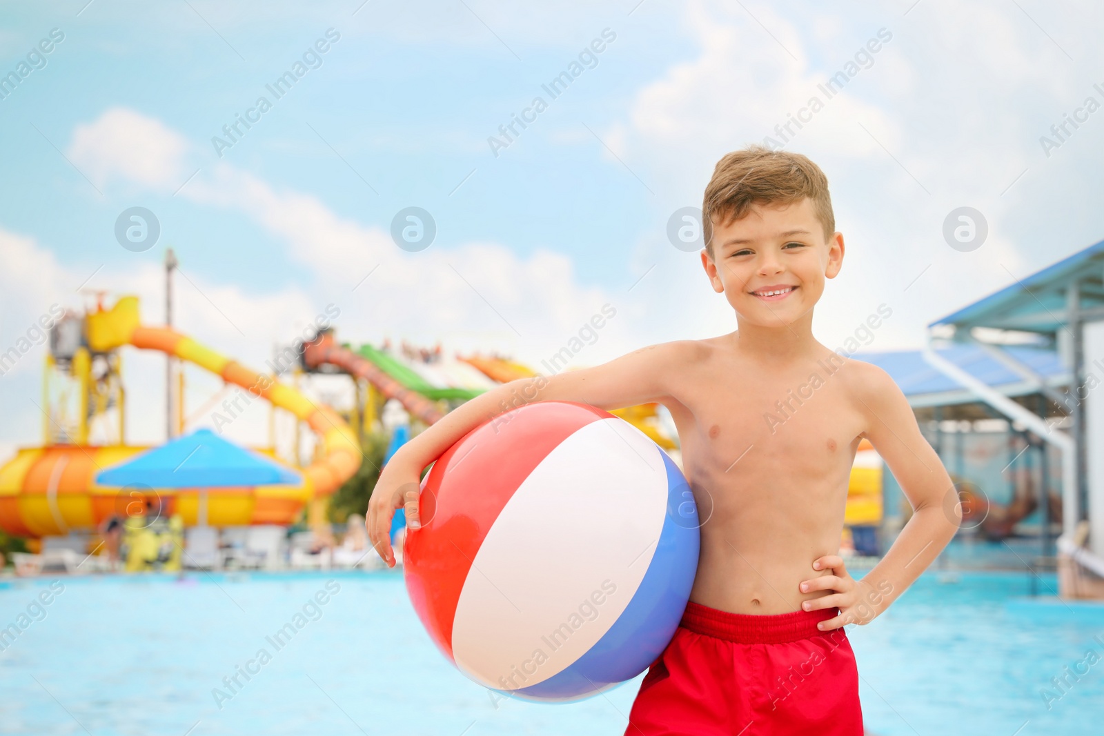 Photo of Cute little boy with inflatable ball near pool in water park, space for text