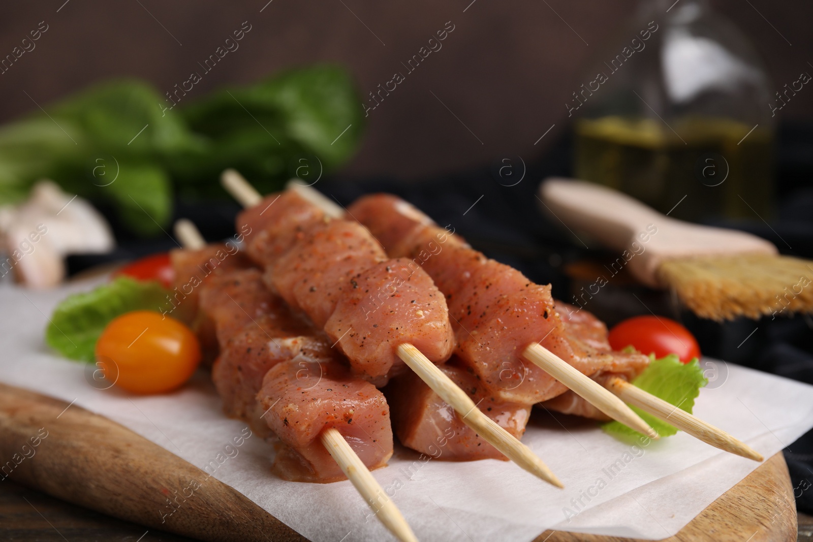 Photo of Skewers with cut raw marinated meat on wooden table, closeup