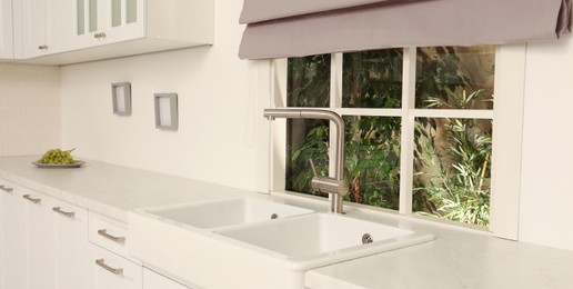 Image of White sink with tap near window in kitchen. Interior design