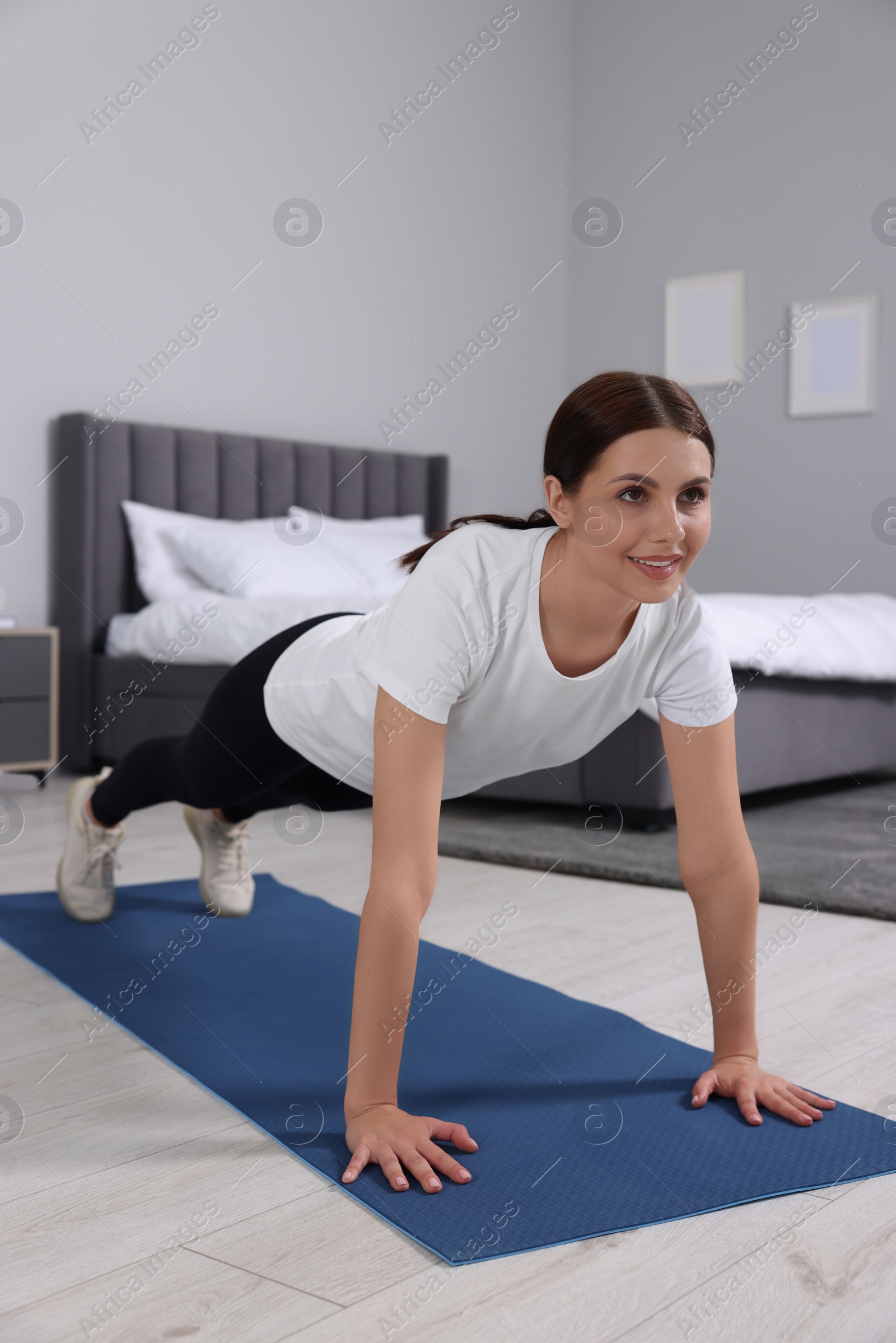 Photo of Happy woman doing plank exercise at home. Morning routine
