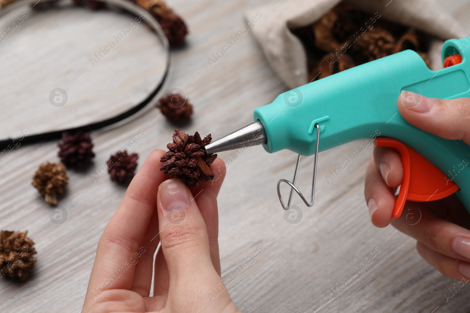 Photo of Woman with hot glue gun making craft at wooden table, closeup