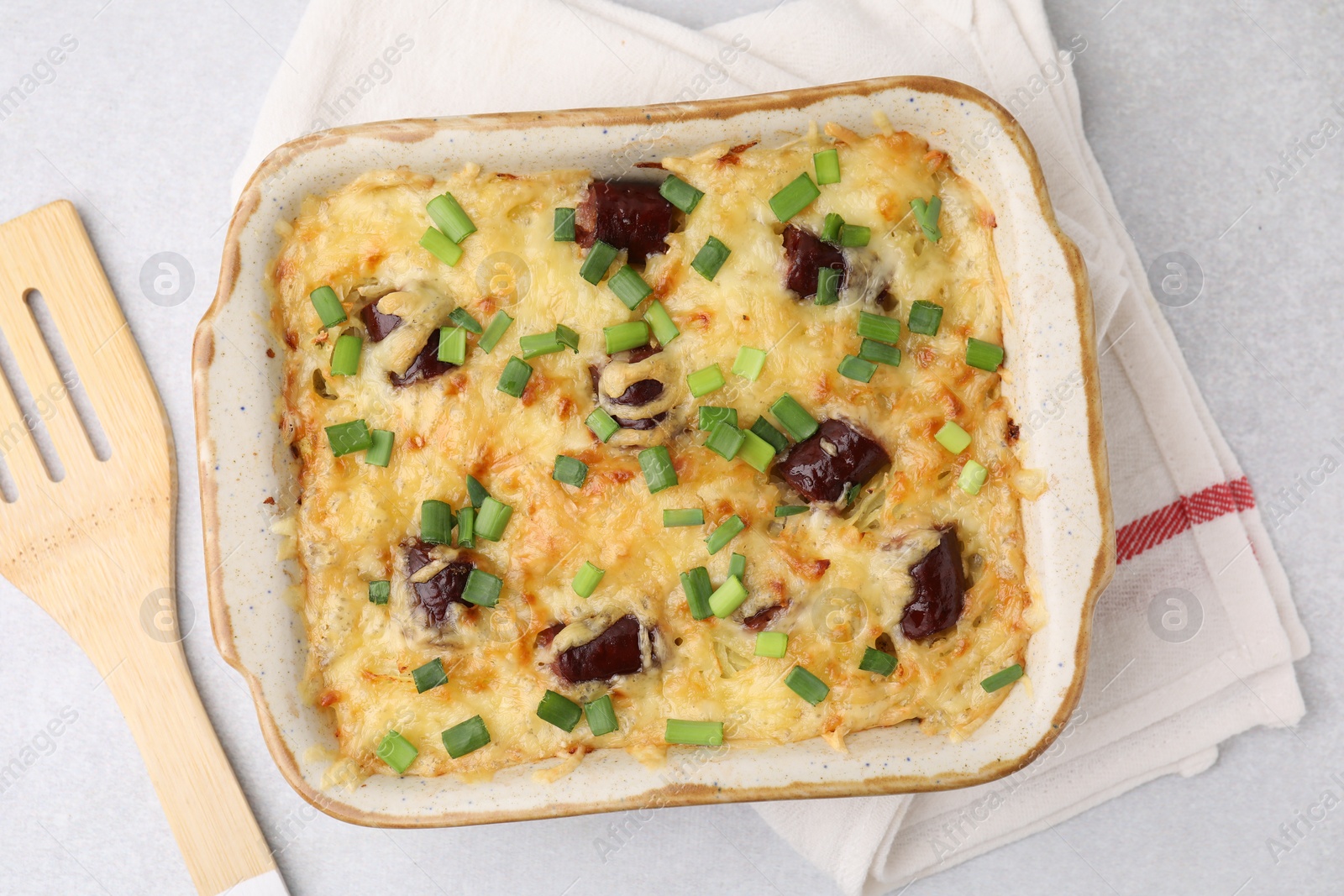 Photo of Tasty sausage casserole with green onions in baking dish on white table, top view