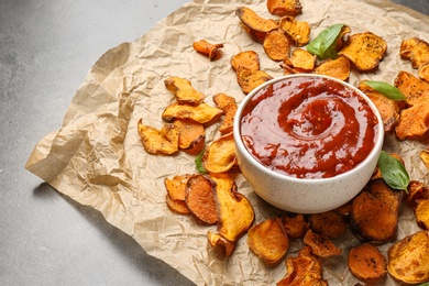 Photo of Sweet potato chips and bowl of sauce served on grey table