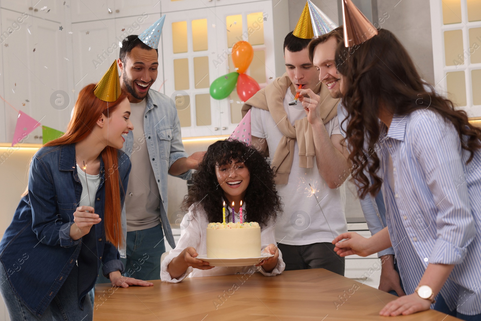 Photo of Happy friends with tasty cake celebrating birthday in kitchen