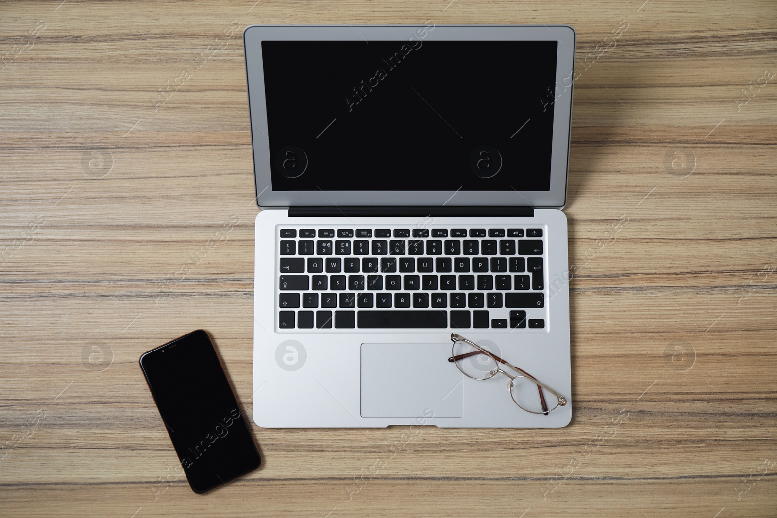 Photo of Modern laptop, smartphone and glasses on wooden table, flat lay. Space for design