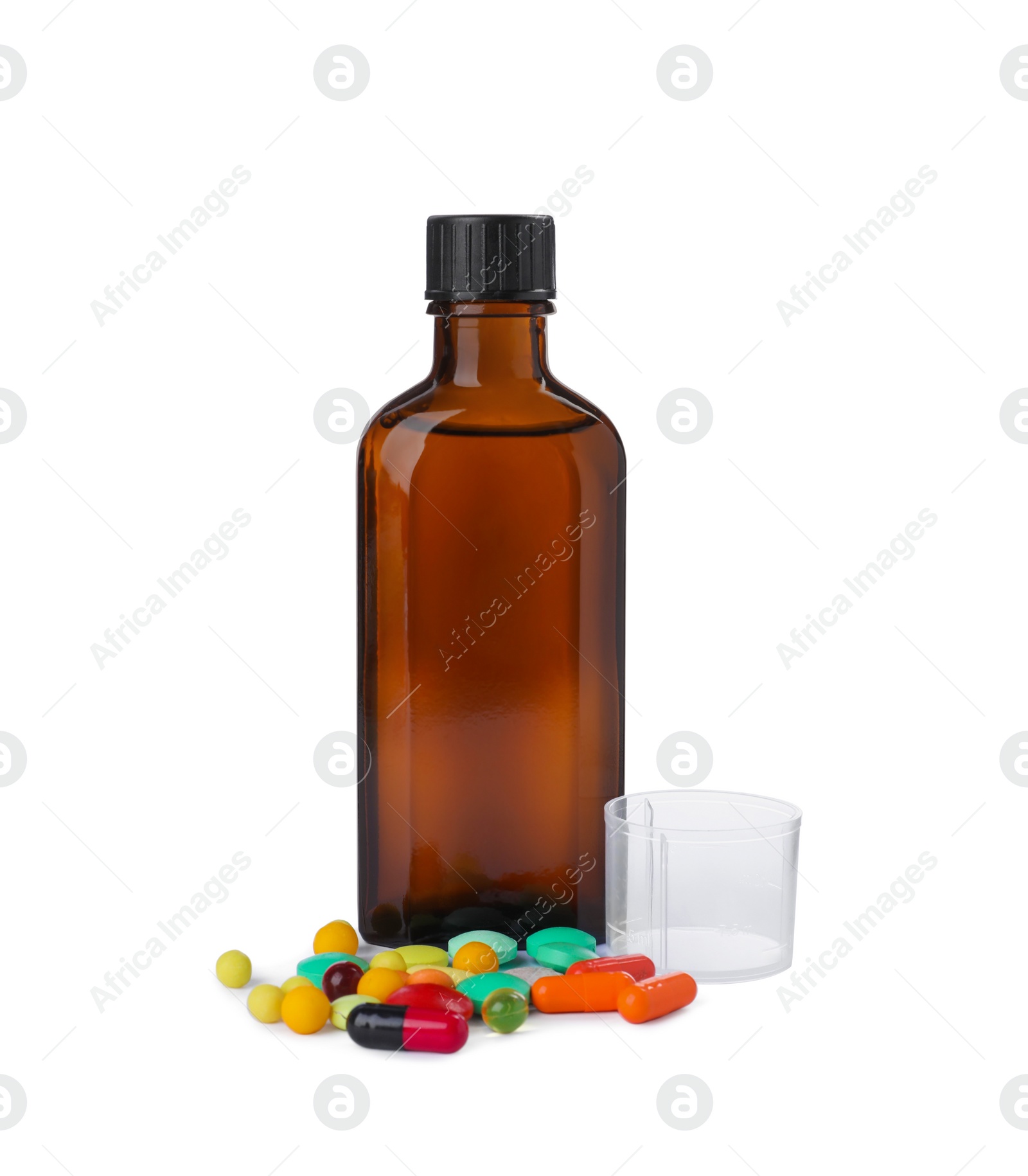 Photo of Bottle of syrup, measuring cup with pills on white background. Cough and cold medicine