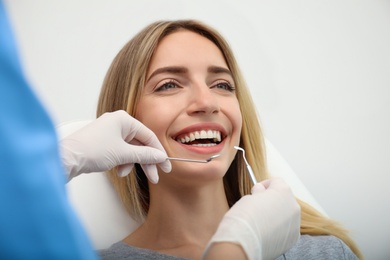 Photo of Doctor examining patient's teeth on light background, closeup. Cosmetic dentistry