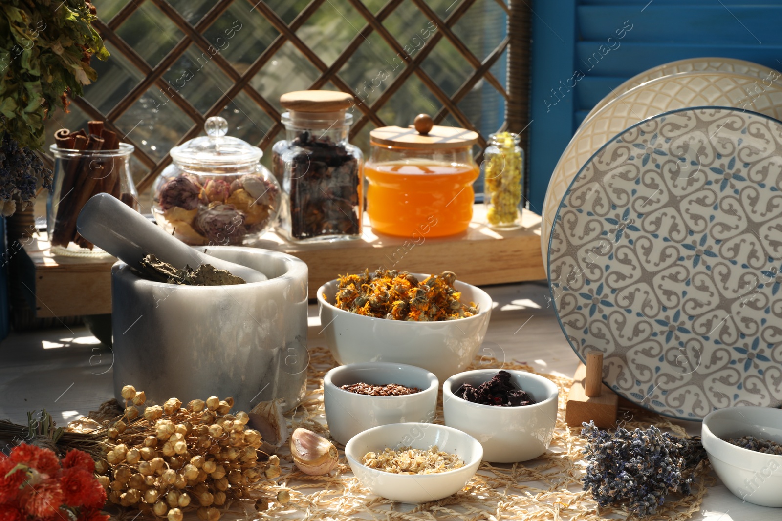 Photo of Many different dry herbs, flowers and plates on table near window