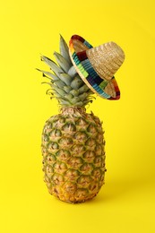 Photo of Pineapple with Mexican sombrero hat on yellow background