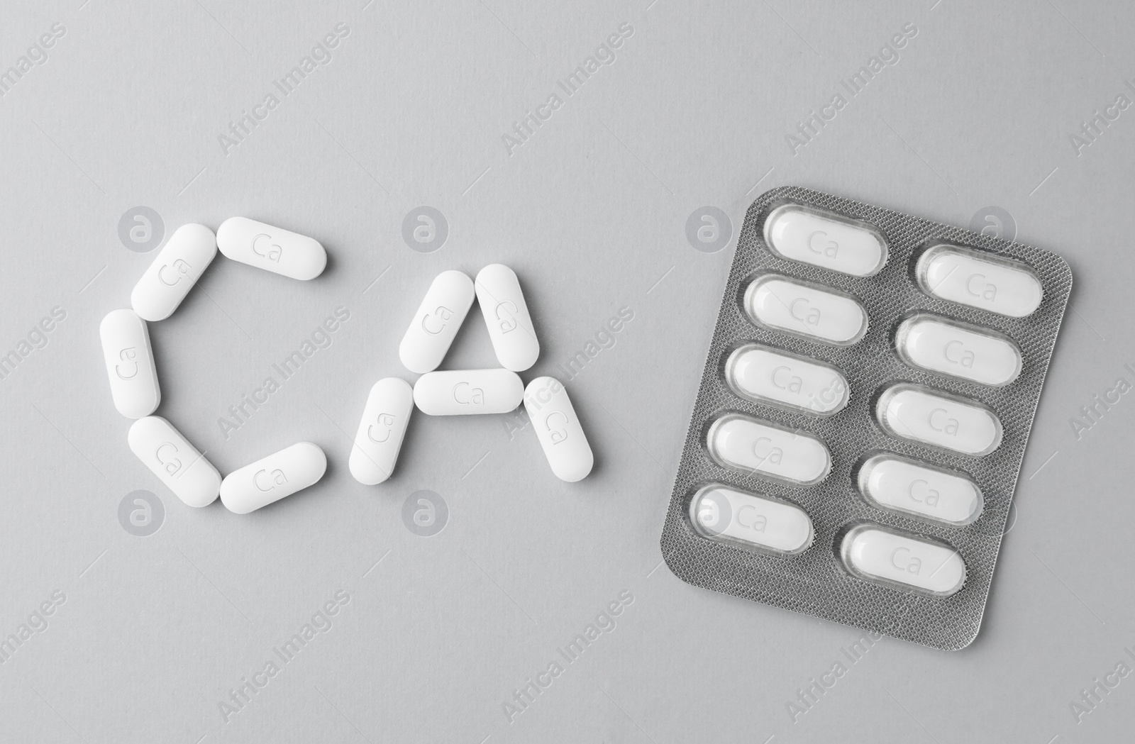 Photo of Blister pack with calcium supplement pills on light grey background, flat lay