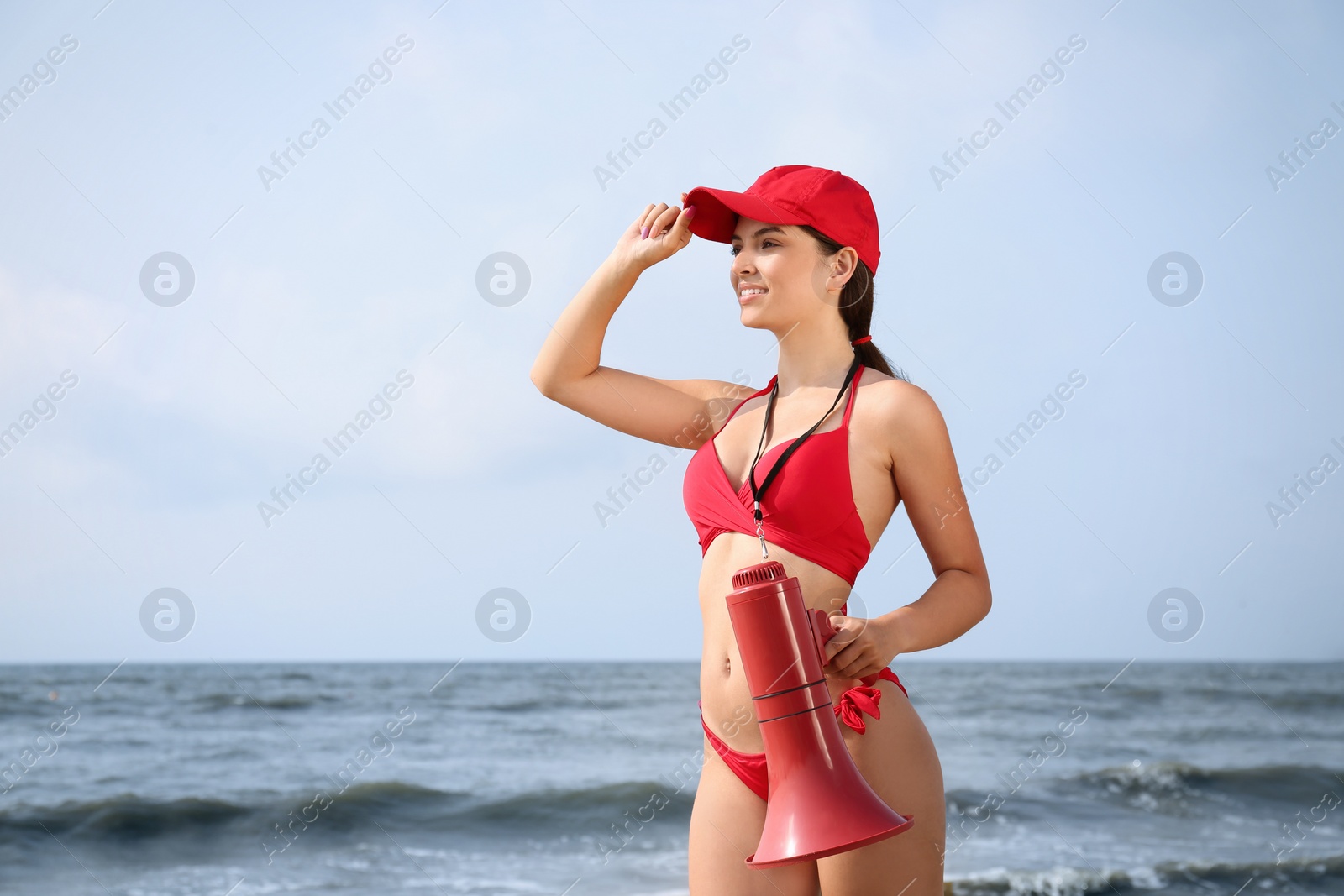 Photo of Beautiful young lifeguard with megaphone near sea