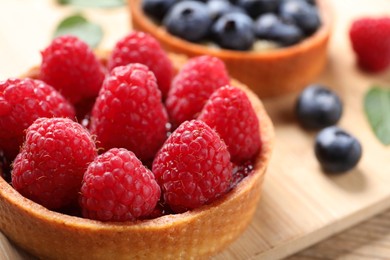 Photo of Tartlet with fresh raspberries on board, closeup. Delicious dessert