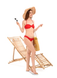 Young woman with beach accessories near sun lounger against white background