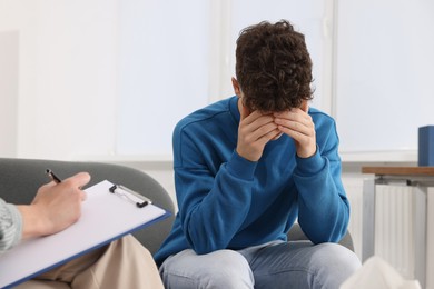 Photo of Psychologist working with teenage boy in office, space for text. Teenager problems
