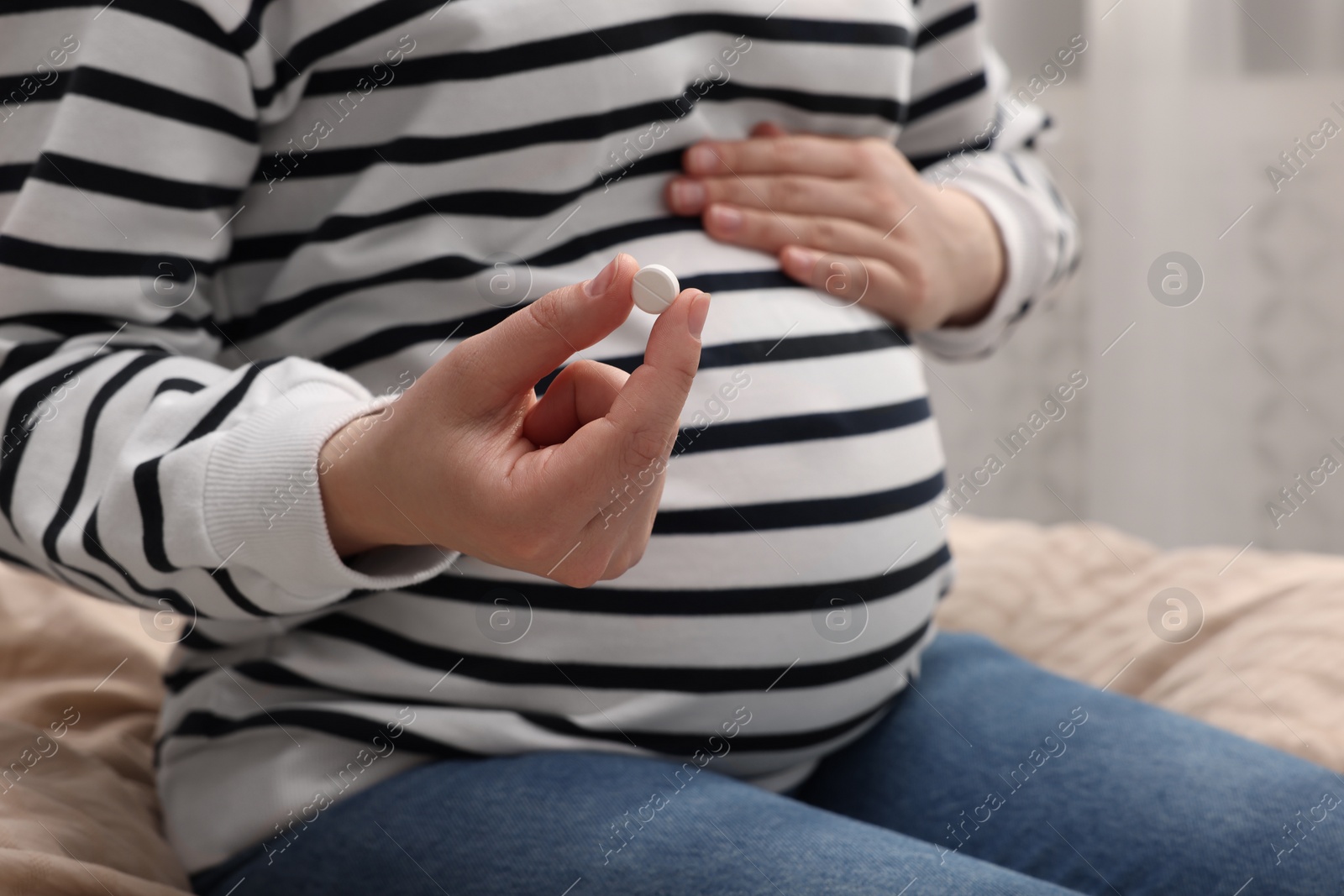 Photo of Pregnant woman with pill at home, closeup