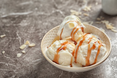 Tasty ice cream with caramel sauce in bowl on table