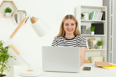Photo of Home workplace. Portrait of woman near laptop at white desk in room