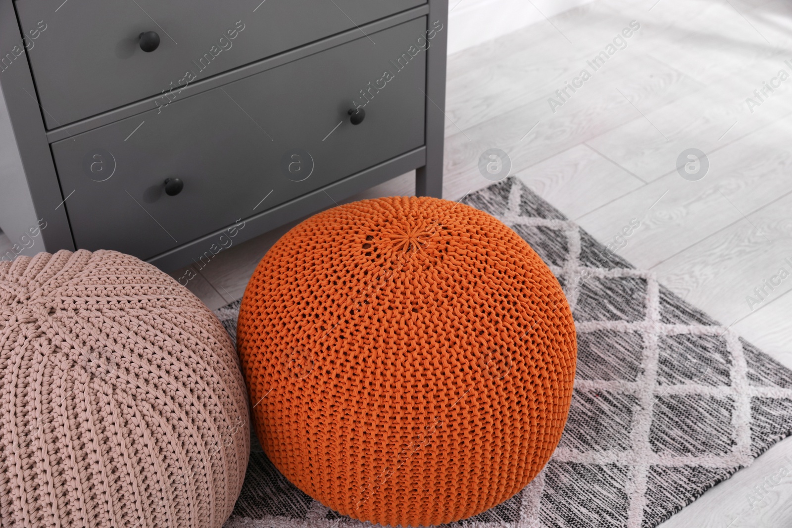 Photo of Stylish poufs near grey chest of drawers in room. Interior design