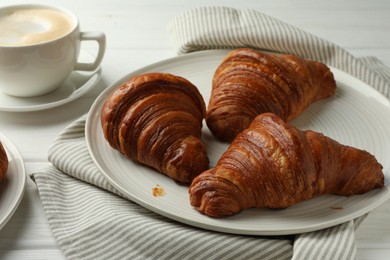 Plate with tasty croissants on white wooden table, closeup