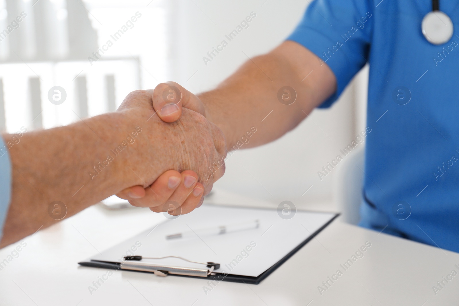 Photo of Doctor and senior patient shaking hands in office , closeup