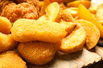 Photo of Tasty fried chicken nuggets on serving board, closeup