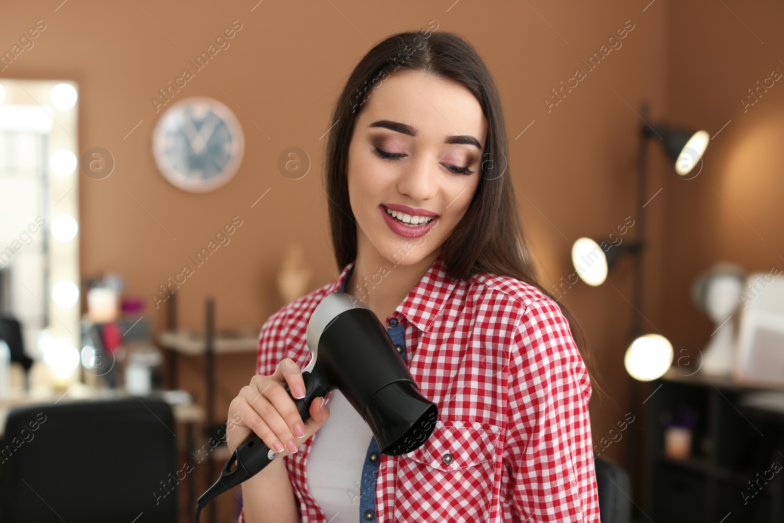 Photo of Professional hairdresser with blow dryer in beauty salon