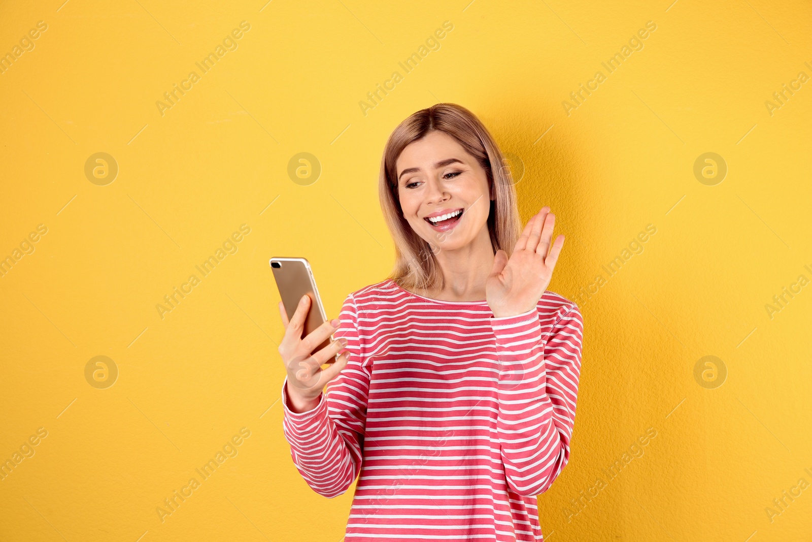 Photo of Woman using mobile phone for video chat on color background