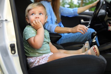 Photo of Mother with cigarette and child in car, focus on little girl. Don't smoke near kids