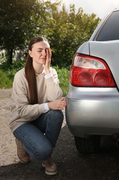 Stressed woman near car with scratch outdoors