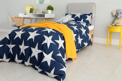 Photo of Bed with star patterned linens in child's bedroom. Interior design