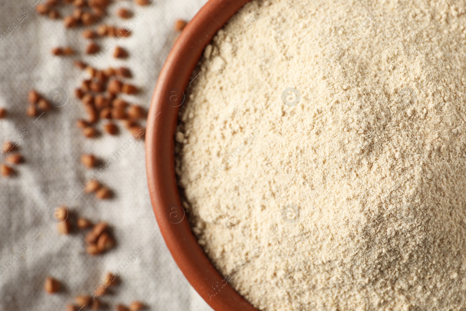 Photo of Bowl of buckwheat flour on cloth, top view