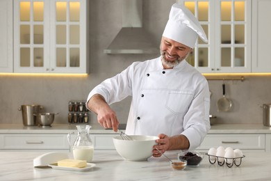 Professional chef making dough at white marble table in kitchen