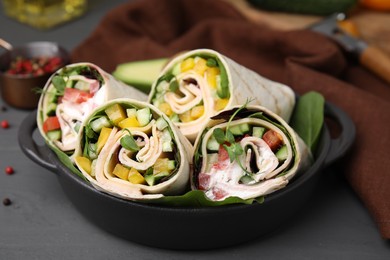 Photo of Delicious sandwich wraps with fresh vegetables on grey table, closeup