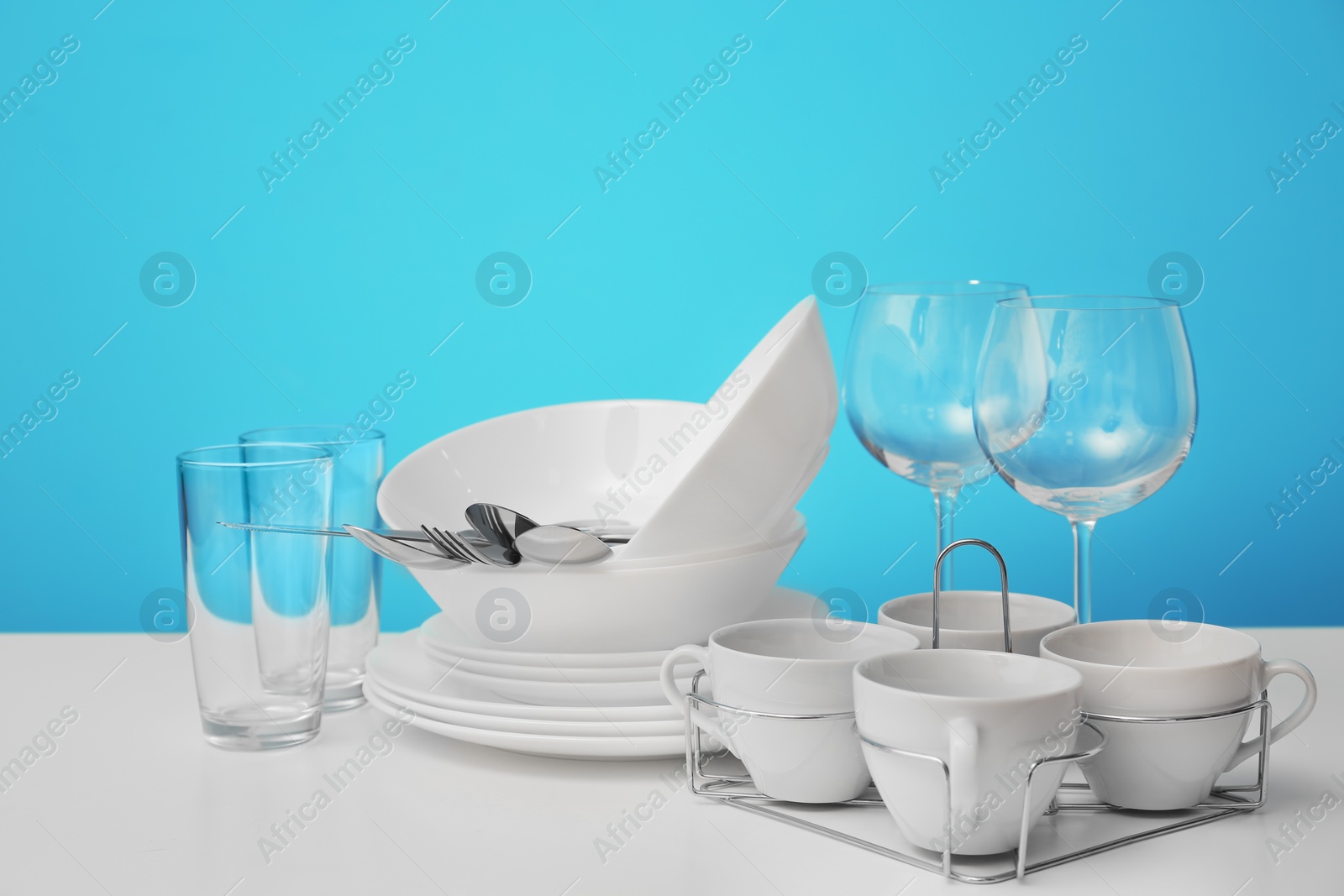 Photo of Set of clean dishware on table against color background