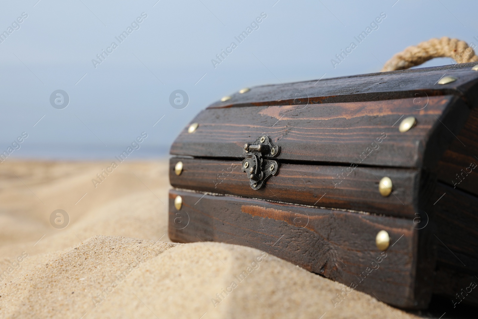 Photo of Closed wooden treasure chest on sandy beach