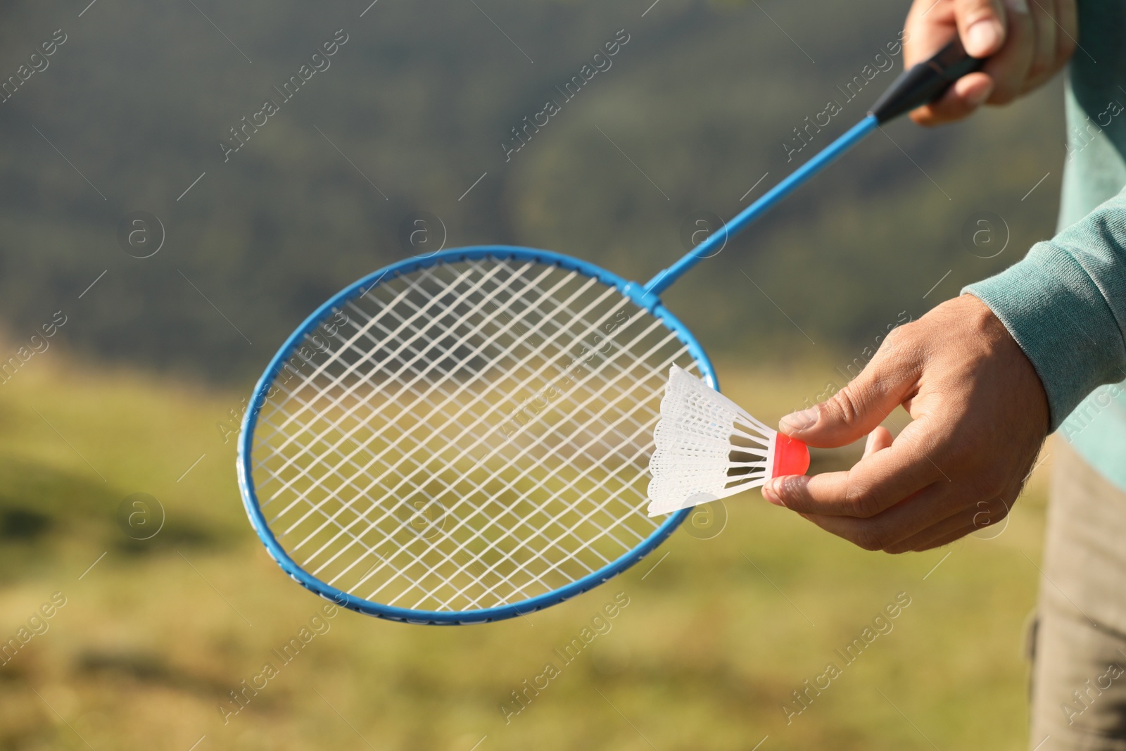 Photo of Man playing badminton outdoors on sunny day, closeup