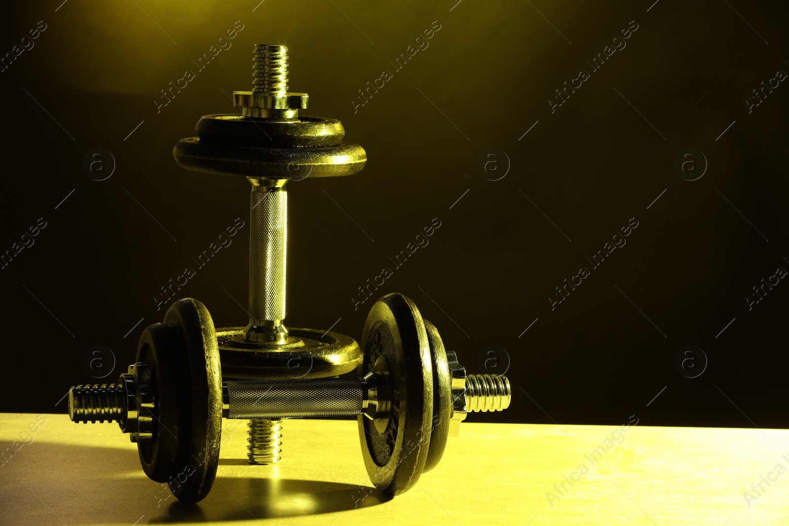 Photo of Two barbells on table in color lights. Space for text