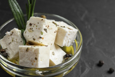 Photo of Pickled feta cheese in bowl on dark grey table, closeup