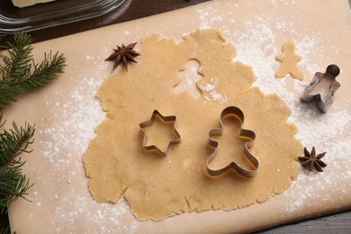 Photo of Making Christmas cookies. Flat lay composition with cutters and raw dough on wooden table