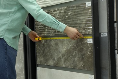 Man using tape measure while choosing tile in store, closeup