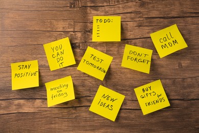 Photo of Paper notes with different phrases on wooden table, flat lay