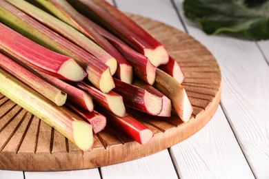 Photo of Many cut rhubarb stalks on white wooden table, closeup