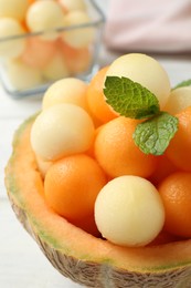 Different melon balls with mint on white table, closeup