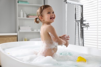 Photo of Cute little girl in foamy bath at home