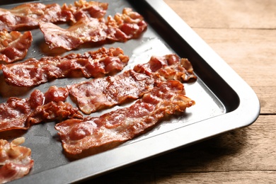 Photo of Baking sheet with bacon on table, closeup